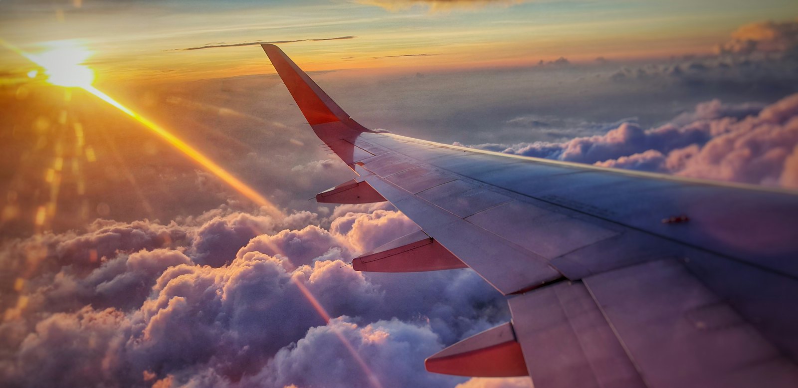 Aircraft wing above the clouds at sunset